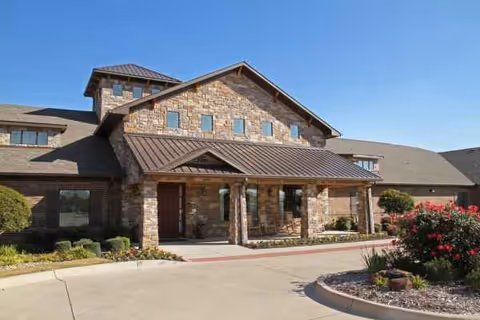 Stonefield Assisted Living and Memory Care exterior with a stone facade and landscaped entrance.