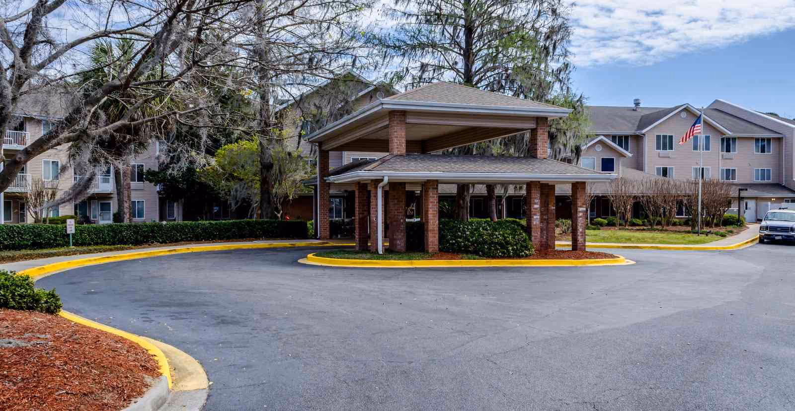 Brick entry pavilion with a circular driveway in front of a senior living building.