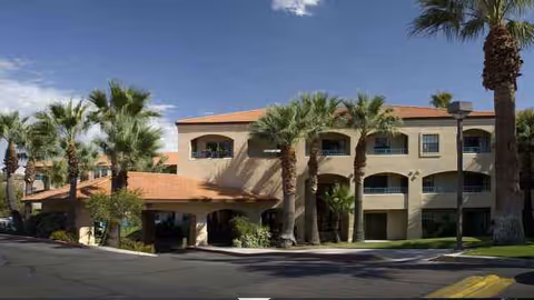 Exterior of Atria Campana del Rio with palm trees and arched entrances.