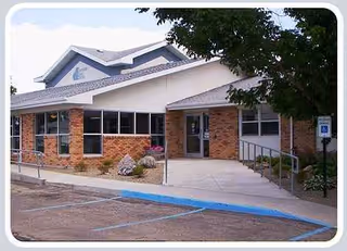 Front exterior of Napoleon Care Center: single-story brick building with accessibility ramp and entrance.