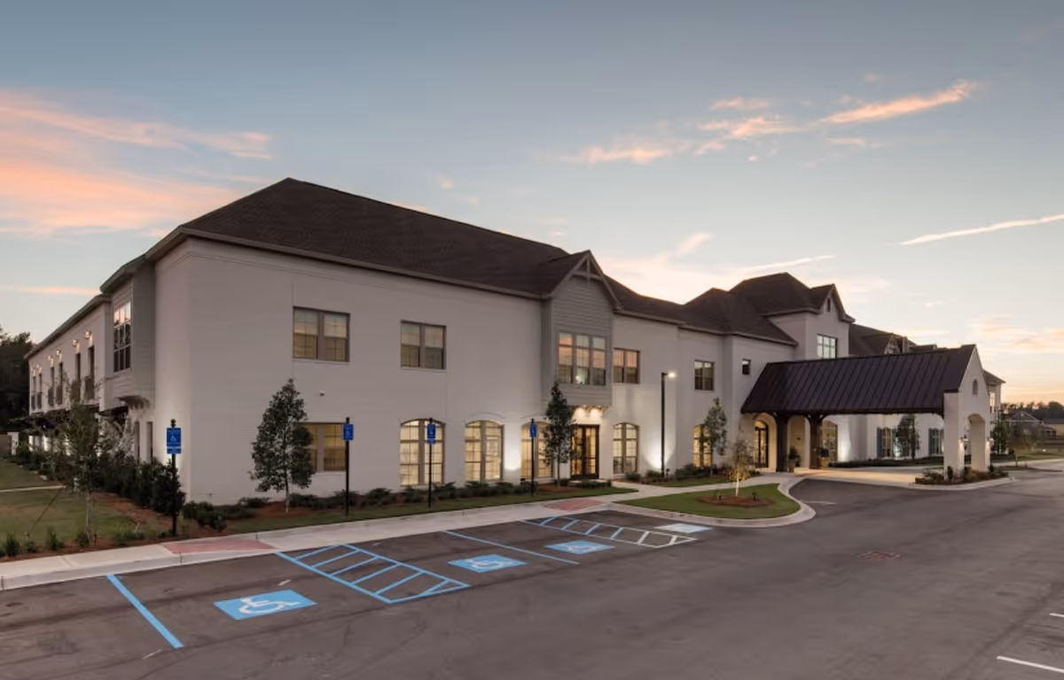 White brick senior living facility exterior with curved entrance and handicap parking