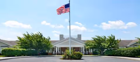 American flag flies in front of Celebration Villa Lebanon PA, a single-story senior living facility entrance.