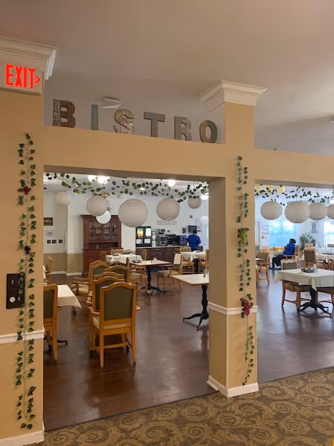 Dining room area labeled 'Bistro' with tables and chairs, hanging paper lanterns and ivy garlands.