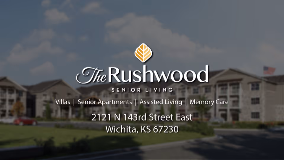 Exterior view of The Rushwood Senior Living facility with a clear sky and an American flag visible. The image includes text overlay with the facility's name, services offered, and address in Wichita, KS.