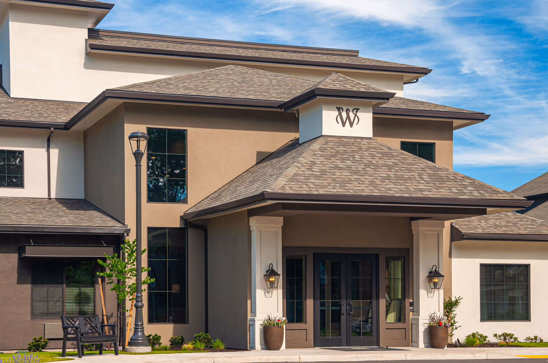 Exterior view of Weatherly Inn independent senior living facility front entrance with benches and planters.