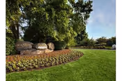 Green lawn, curved flower beds, and Granite Farms Estates sign at entrance.