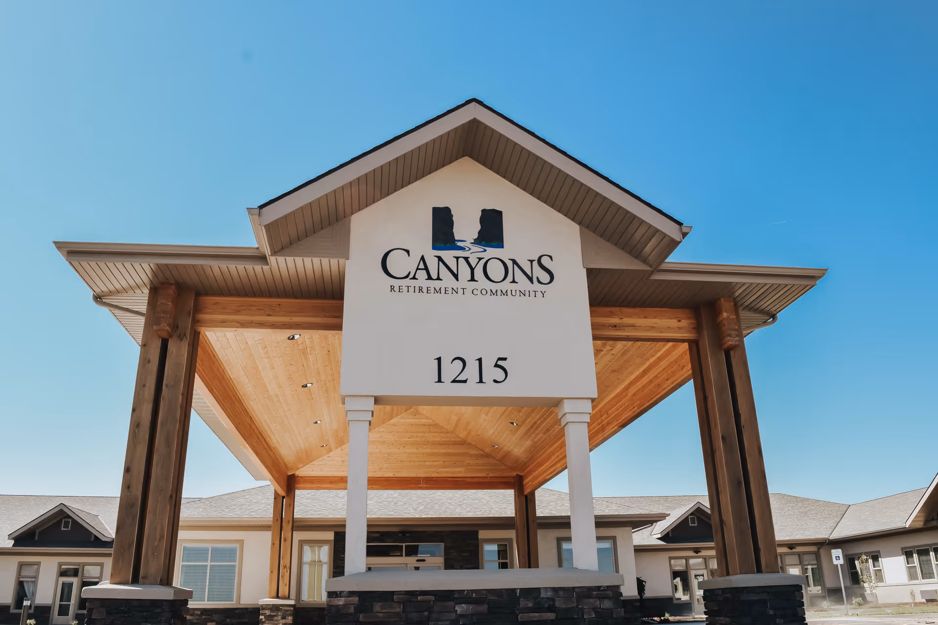 Front view of Canyons Retirement Community entrance with sign and blue sky.
