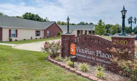 Exterior view of Victorian Place of Washington Senior Living with brick entrance sign and landscaping.