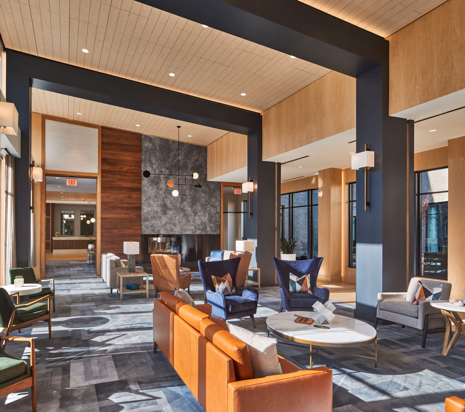 Spacious, modern communal lounge with leather sofas, armchairs, coffee tables, high ceilings, large windows, and a fireplace.