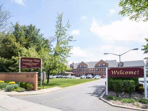 Entrance to Dominican Village senior living with welcome sign and brick building.