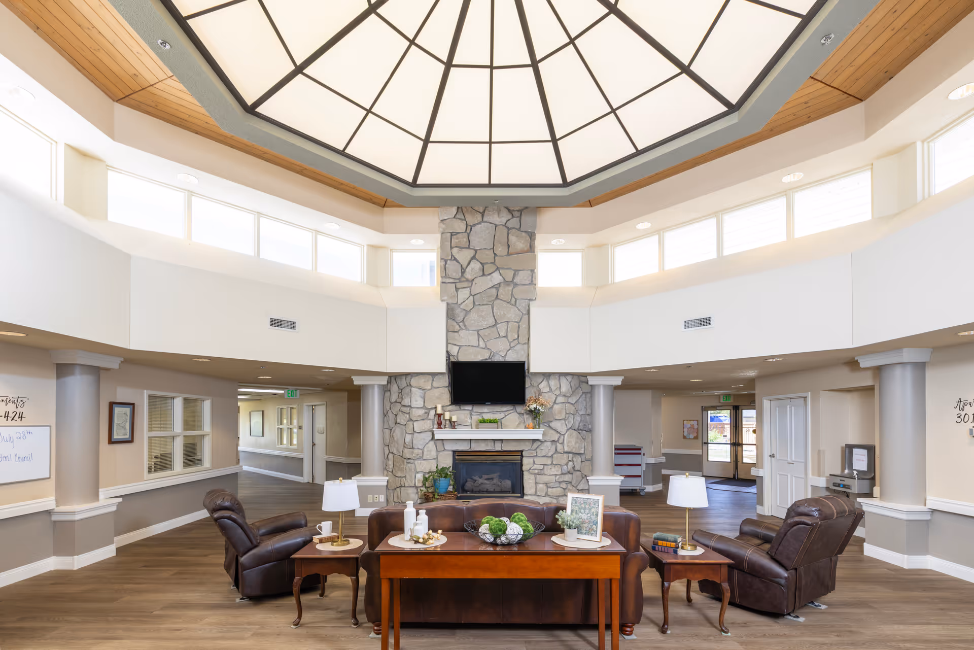 Interior view of a spacious and well-lit common area featuring a stone fireplace and comfortable seating.