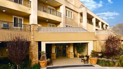 Exterior view of Atria Golden Creek with accessible entrance, balconies, and potted plants.