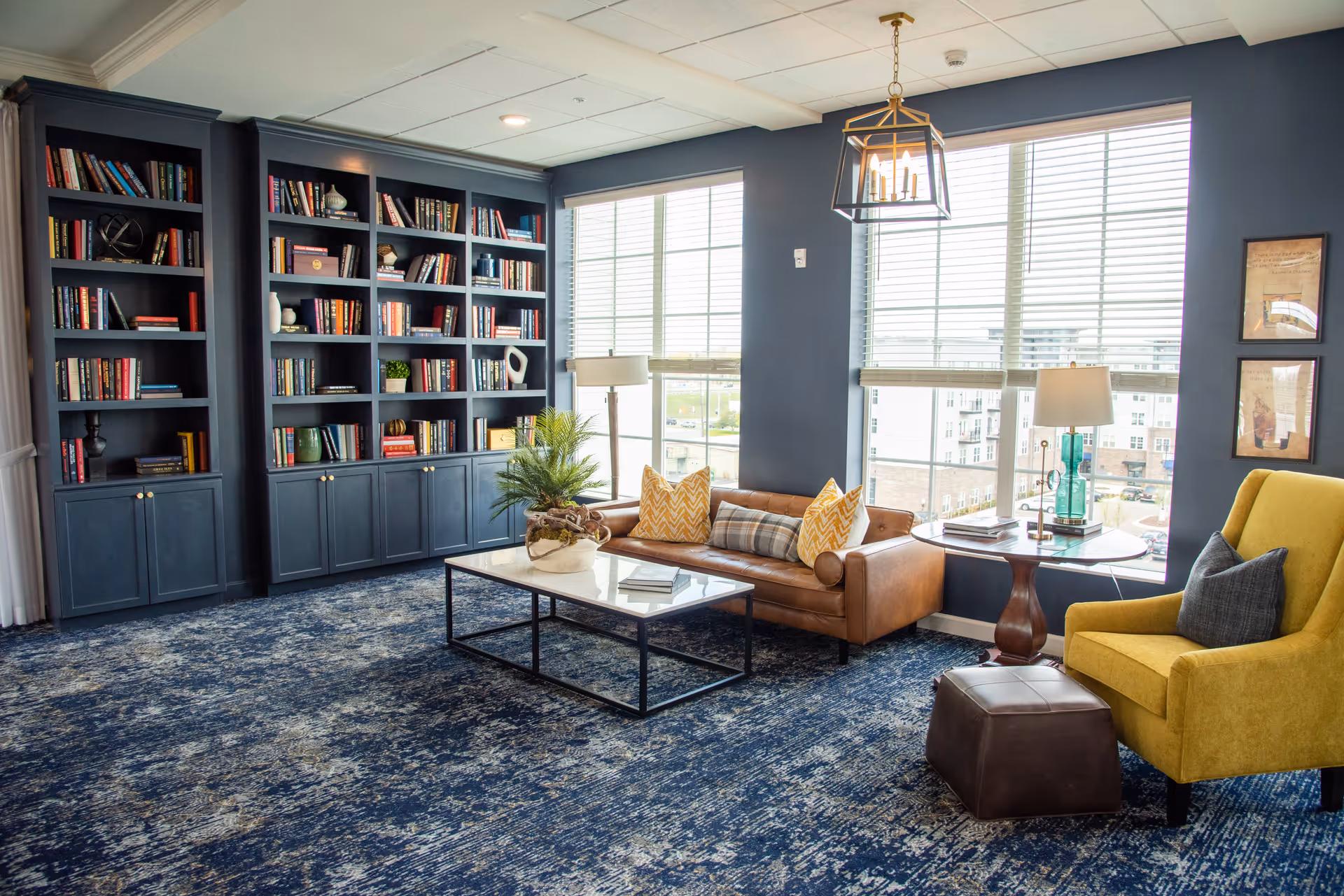 A bright lounge with built-in bookshelves, a leather sofa, armchair, coffee table and large windows.
