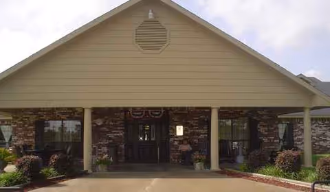 Front entrance of Dogwood Trails Manor with brick pillars and a covered entryway.