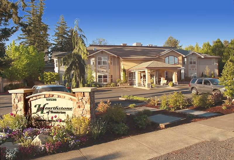 Exterior view of Hearthstone at Murrayhill with sign, landscaping, and parked cars.