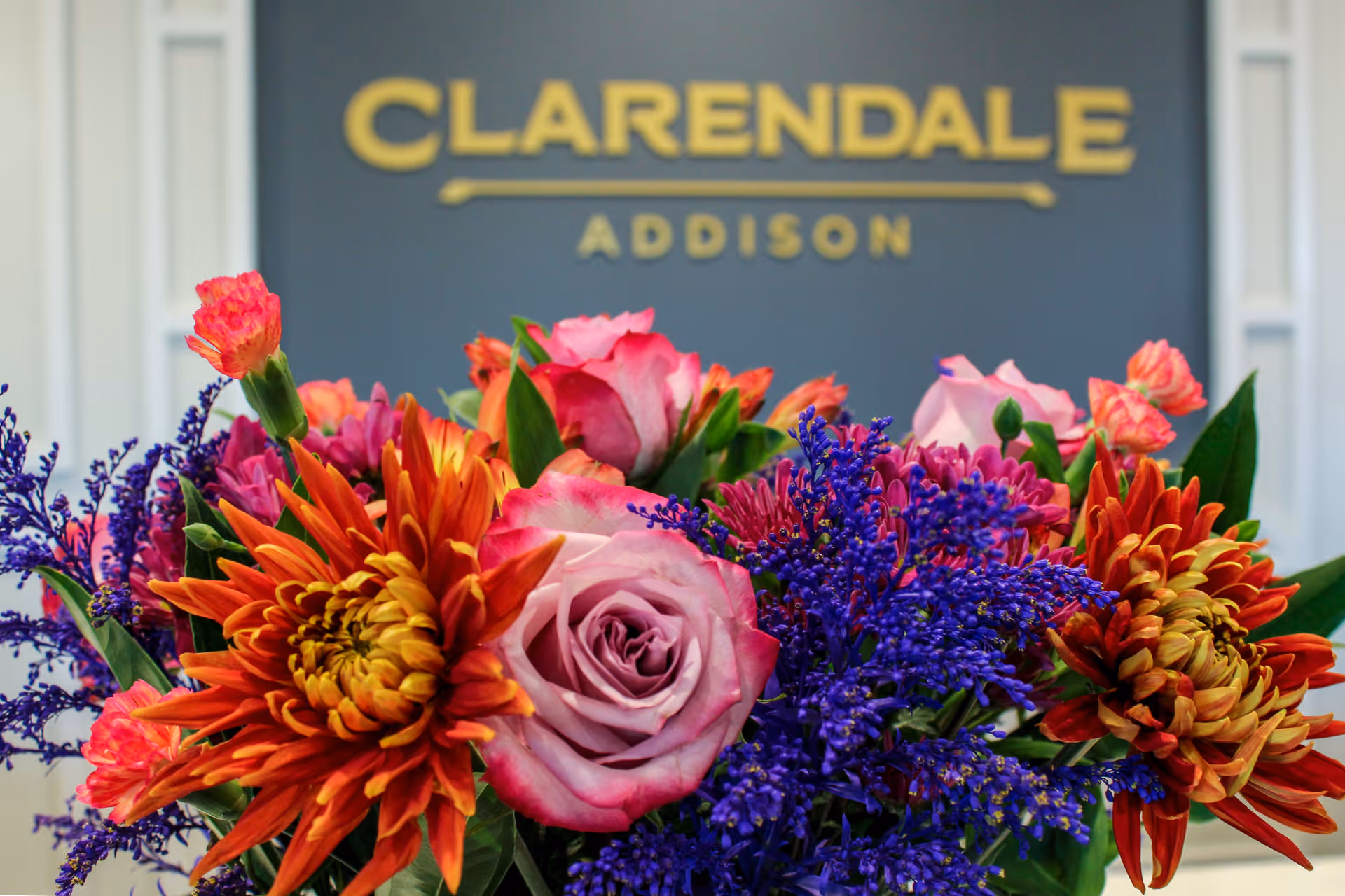 A colorful bouquet of flowers arranged in front of a sign reading "CLARENDALE ADDISON".