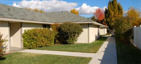 Exterior view of Edgewood Castle Hills: single-story beige building with shrubs and a sidewalk.