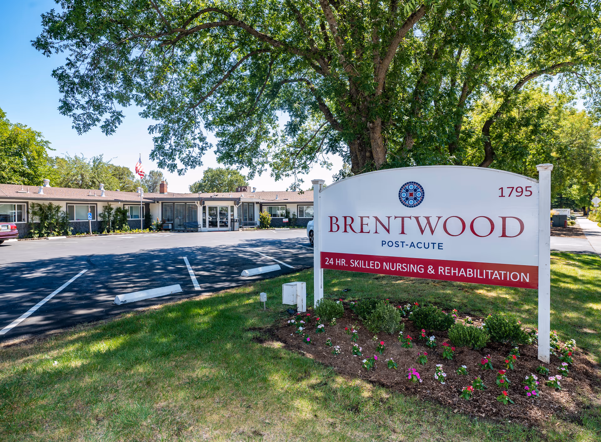 Front exterior of Brentwood Post-Acute facility with a large entrance sign, landscaped bed, and parking lot.