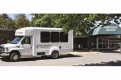 White shuttle parked in front of Pinecrest Manor entrance.