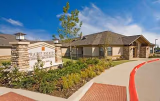 Exterior view of Prairie Estates senior living facility with sign and landscaped entry.