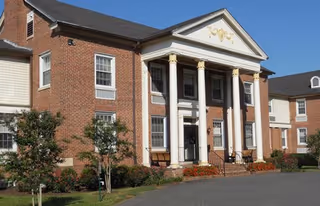 Heritage at Augsburg exterior: brick building with white columns and landscaped entrance