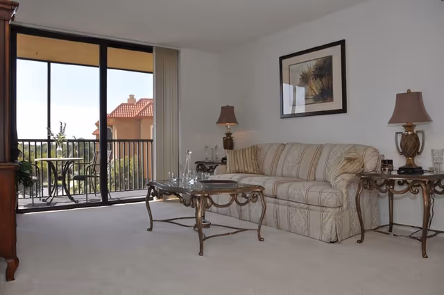 Cozy living room featuring a striped sofa, glass coffee tables, and a balcony view.