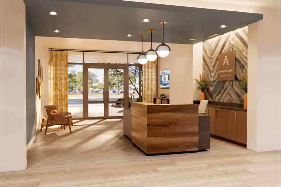 Reception lobby with a wooden front desk, pendant lights, seating, and glass entrance doors.