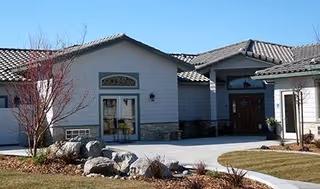 Front exterior view of Ada's Lodges Mission Lodge with curved walkway and landscaping.
