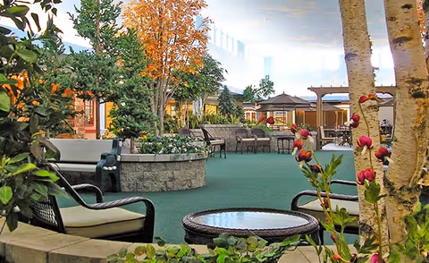 Indoor atrium-style common area with seating, potted trees, and tables.