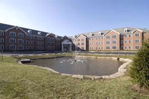 Armour Oaks senior living community exterior with a circular pond and lawn.