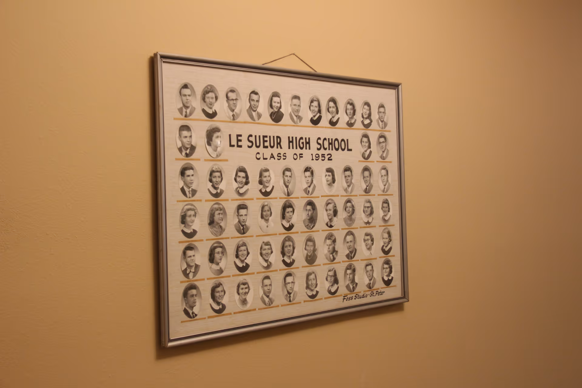 A framed Le Sueur High School Class of 1952 photo collage hanging on a beige interior wall.