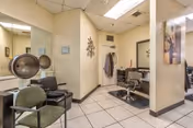 Small interior salon area with styling chairs, a hooded hair dryer, mirrors, and tiled tile flooring.