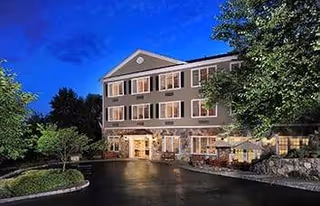 Maplewood Senior Living building, a three-story exterior with windows and landscaped entrance at dusk.