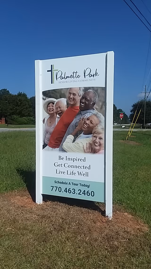 Outdoor sign for Palmetto Park Senior Living Community featuring a group of six smiling diverse seniors and text encouraging to be inspired, get connected, and live life well, with a phone number to schedule a tour.