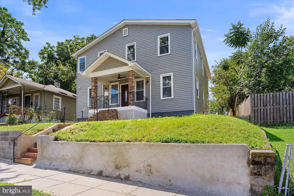 Apex Assisted Living facility featuring a two-story gray house with a porch and green lawn.