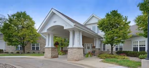 A senior living facility entrance with a covered drive-through canopy and landscaped grounds.