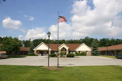 A single-story senior living facility exterior with a flagpole and parking lot.