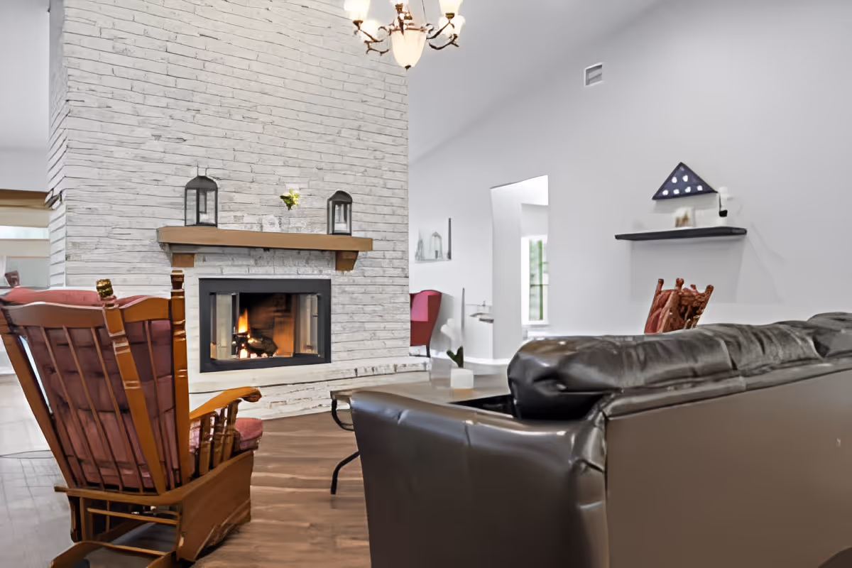 Cozy living room with a stone fireplace, leather sofa, and wooden rocking chair.