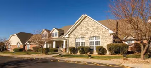 Exterior front view of a senior living facility with stone facade.
