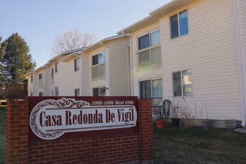 Exterior view of a two-story senior residence with a brick sign displaying Casa Redonda De Vigil