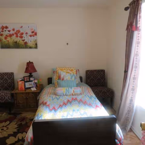 A single bed with a colorful quilt in a small bedroom.