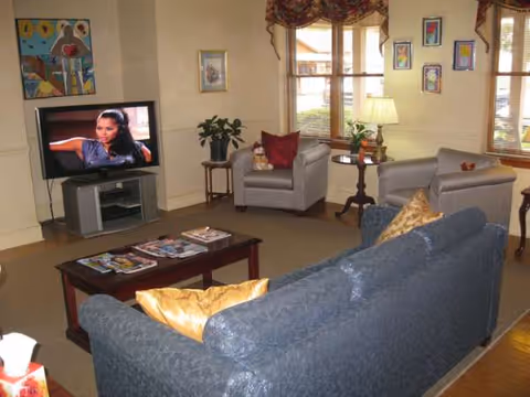 A cozy senior living lounge with couches, a coffee table, and a TV.
