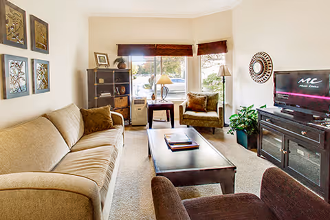 Furnished living room with a sofa, armchairs, coffee table, TV console and a window.