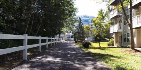 Pillsbury Manor exterior with a paved path, white fence, and trees.