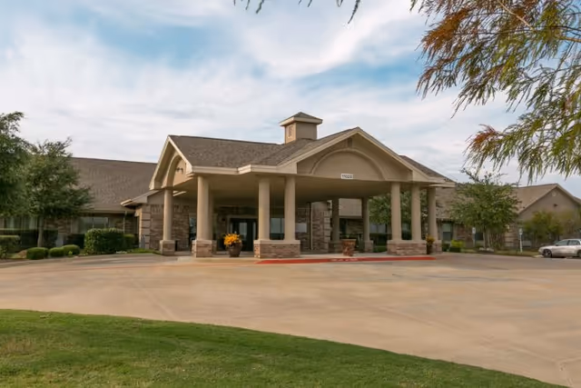 Front exterior view of Legend Oaks Healthcare and Rehabilitation - North Austin building with a covered entrance supported by columns, surrounded by trees and a parking area.