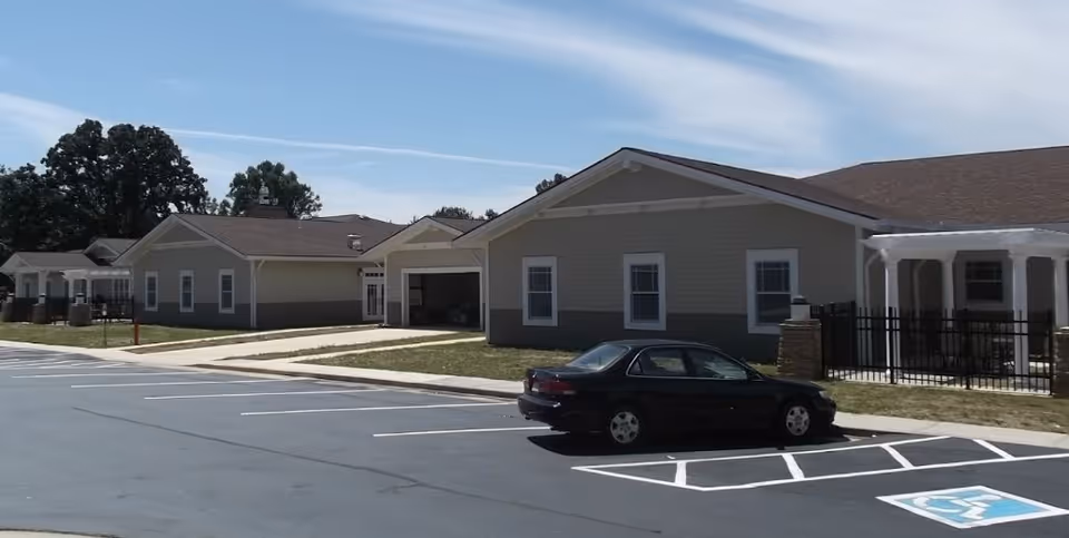 Front exterior of a single-story health and rehab building with a parked car and marked handicap parking spaces.