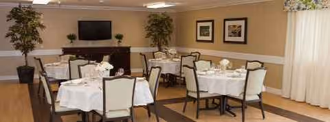 Dining room at Vista Manor Nursing Center with round tables and white tablecloths.