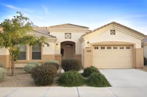 Exterior of a desert-style senior living facility with a driveway and garage.