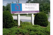 Outdoor signboard for The Jewish Home Residence, framed by trimmed shrubs