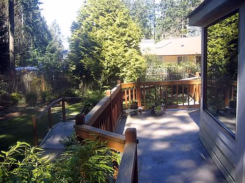Outdoor wooden deck with stairs, railing, and potted plants beside a building.